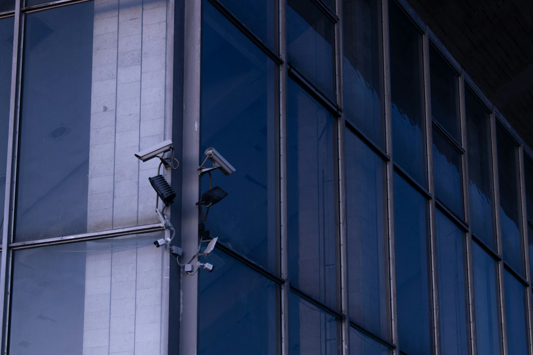 Surveillance cameras installed on the facade of a glass office building